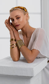 Woman wearing gold bracelets and a headband against a white background