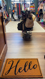 Clothing store interior with a 'Hello' doormat at the entrance.