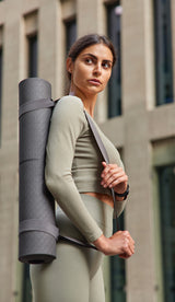 Woman holding a yoga mat against a building background