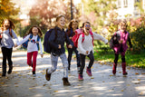 Kids running happily after school, wearing colorful backpacks, promoting secondhand youth apparel and accessories from an online thrift store.