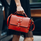 Stylish leather handbag displayed prominently in the hand of a woman wearing a black dress in an urban area, highlighting the charm of purchasing a secondhand from an online thrift store. 