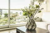A charming vase with flowers staged on an end table in a cozy living room, promoting home goods available from a thrift store with online shopping.