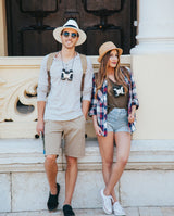 Two people posing together outdoors, wearing hats and casual clothing.

